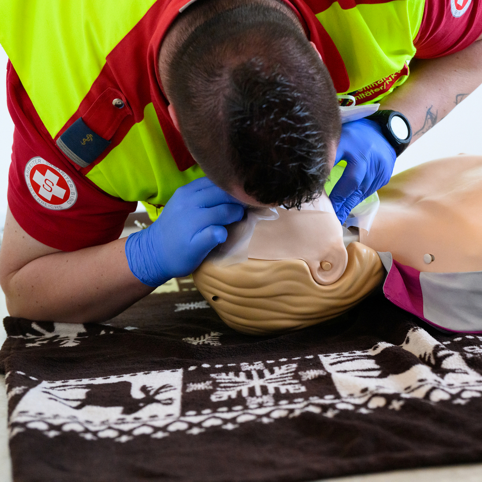 Erste-Hilfe-Trainer in Samariterbund-Uniform demonstriert Mund-zu-Mund-Beatmung