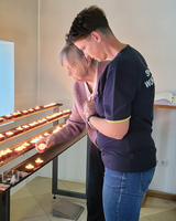 Zwei Frauen zünden Kerzen in einem stillen Raum an.